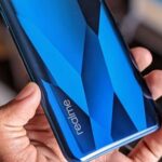Foto com foco no logo da Realme na traseira de um smartphone na cor azul.