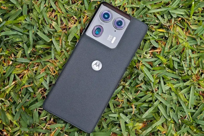 Foto do Motorola Edge 50 Ultra na cor preta com a traseira virada para cima sobre a grama.