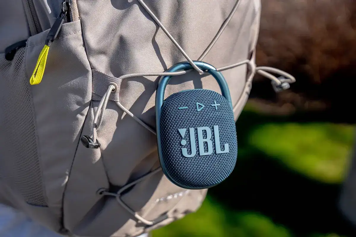 Imagem da JBL Clip 4 Eco pendurada em uma mochila.